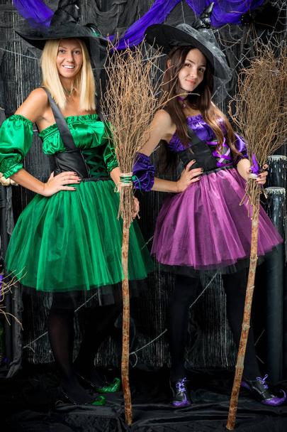 retrato vertical de duas bruxas encantadoras com vassouras para halowe
 - Foto, Imagem