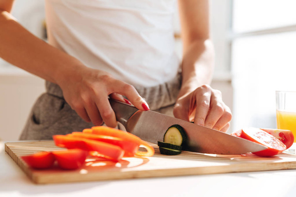 Close up portrait of young woman slicing vegetables - 写真・画像
