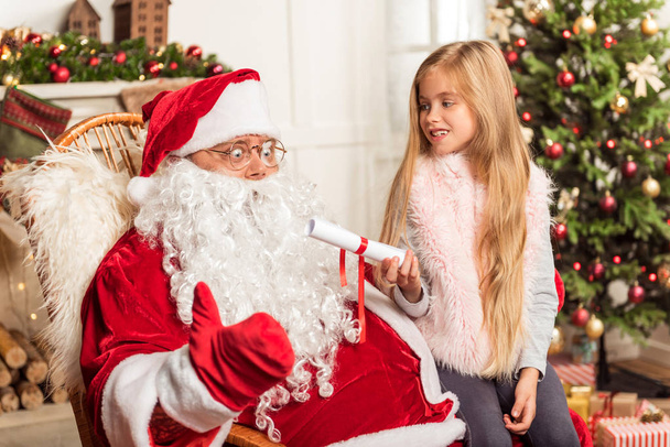 Cheerful female kid talking with Santa Claus - Foto, immagini