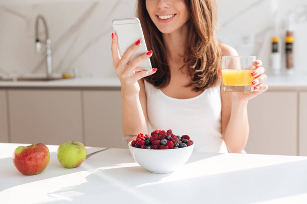 Cropped image of smiling pretty woman looking at mobile phone - Photo, image