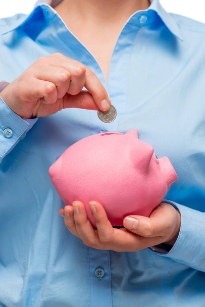 Pink piggy bank and a coin in the hands of a businesswoman close - Foto, afbeelding