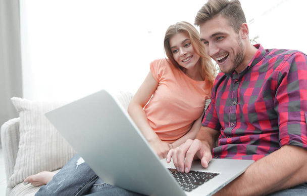 Happy modern couple surfing the net and working on laptop at home - Фото, изображение