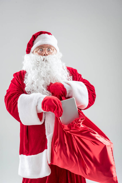 Surprised old man in red costume preparing present on Christmas - Фото, изображение
