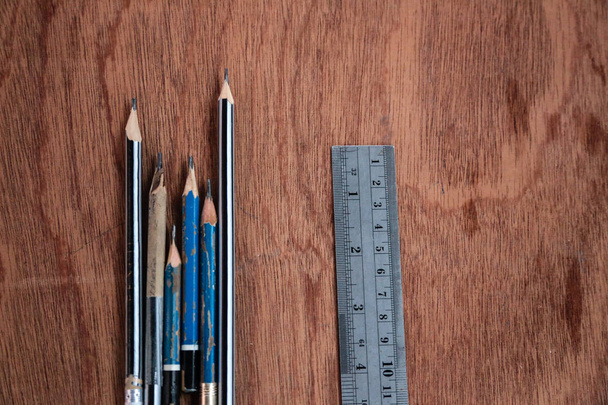 Фотографія має вигляд зверху олівця, а сталева лінійка розміщена на дерев'яній пластині для використання як фон
. - Фото, зображення