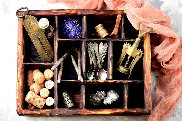 Boîte en bois avec accessoires de cuisine anciens vintage balances à main anglaise, tire-bouchon, cuillères à café, salière, poivrière et plus
. - Photo, image