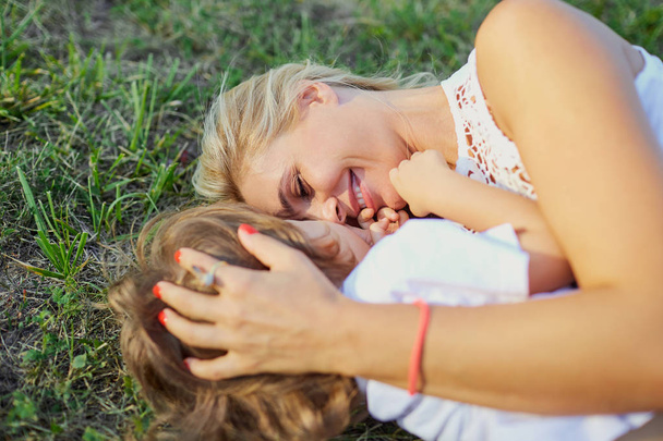 Mother and son are playing hugging on the grass in the park. - Foto, Imagen