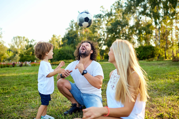 Family playing with a ball in the park. - Фото, изображение