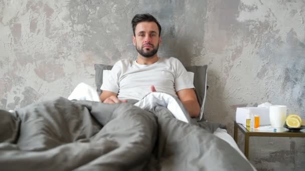 Frustrated bearded gentleman with high temperature wiping nose in bed - Imágenes, Vídeo
