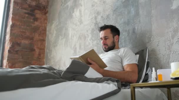 Ill man reading book and feeling sharp twinge of pain - Footage, Video