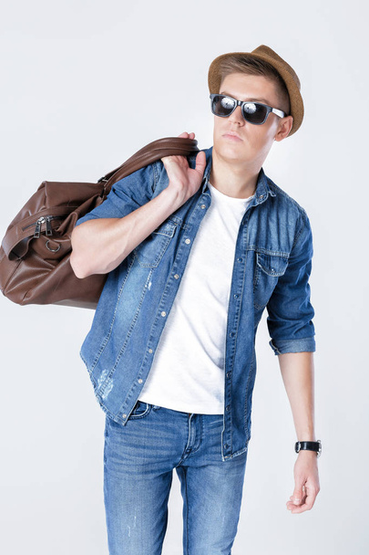 man in hat and sunglasses carrying leather bag on shoulder - Photo, image