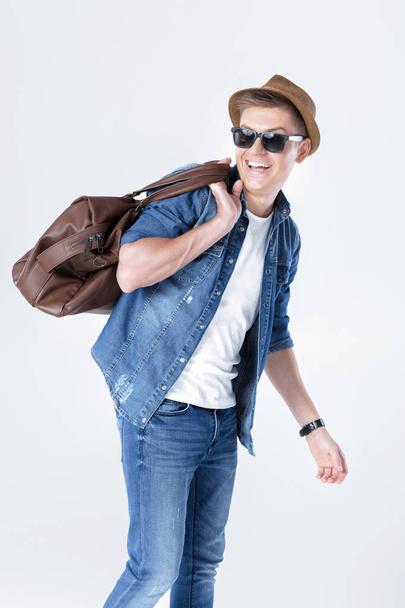 man in hat and sunglasses carrying leather bag on shoulder - Foto, imagen