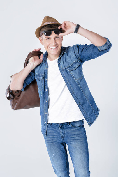 man in hat and sunglasses carrying leather bag on shoulder - Fotó, kép