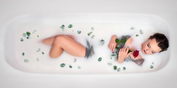 дівчина в ванні з молоком і пелюстками троянд
. - Фото, зображення
