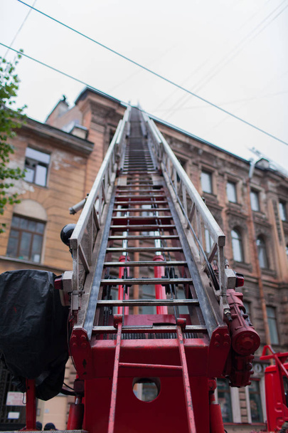 La escalera desplegada camión de bomberos. Los bomberos apagan el techo de la antigua casa
 - Foto, Imagen