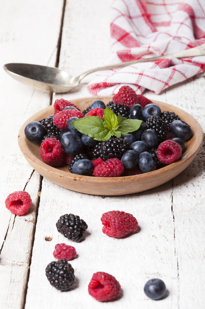 Ripe and sweet berries in bowl on wooden white background - Photo, Image