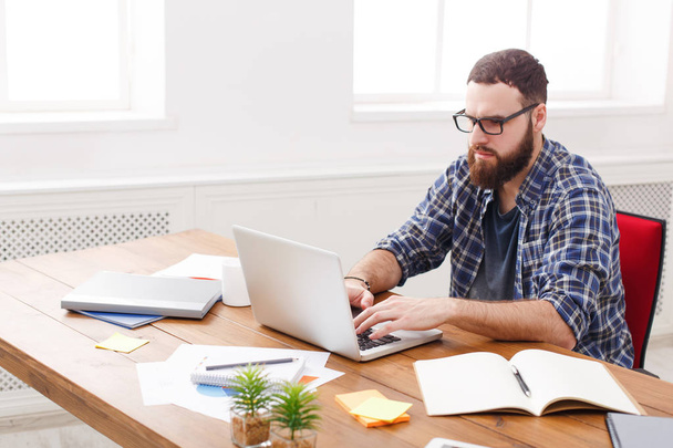 Jeune homme d'affaires travaillant avec un ordinateur portable dans un bureau blanc moderne
 - Photo, image
