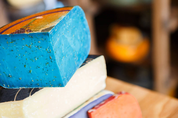Assortimento di formaggio al pesto gouda. Lavanda, blu, viola e rosso sullo sfondo del negozio di alimentari
 - Foto, immagini