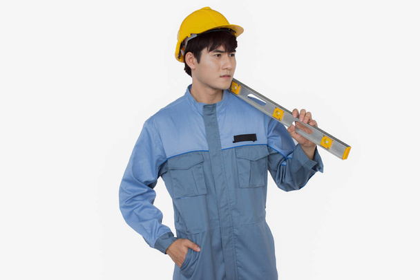 Retrato de un joven trabajador de la construcción que usa casco amarillo en un mecánico uniforme que mantiene el nivel
 - Foto, imagen