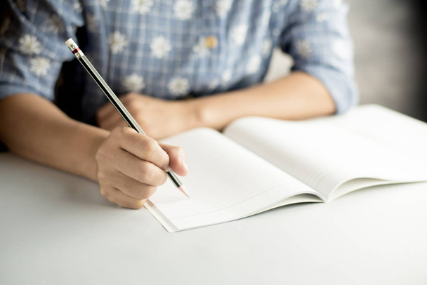 young women writing on blank notebook by black pencil - Фото, зображення