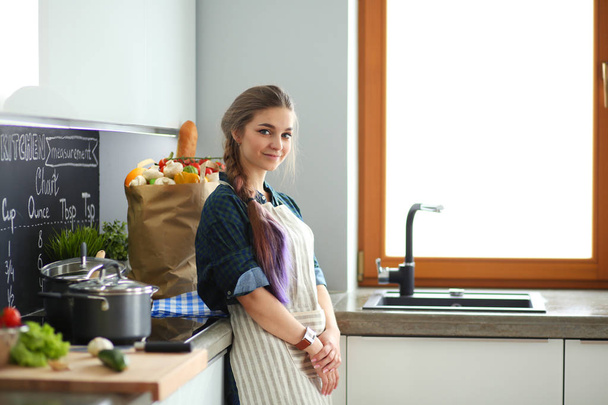 Young woman standing by the stove in the kitchen . - Foto, Imagen