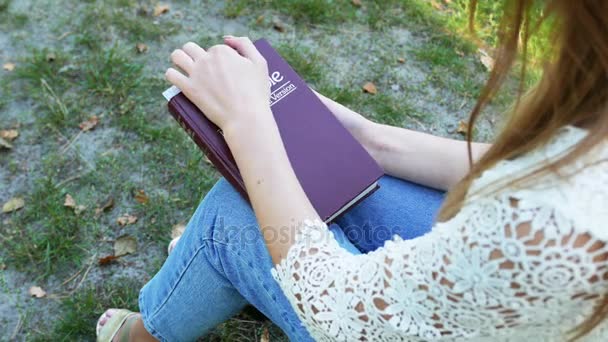 4k. Girl, woman reads  Bible in  summer park  .Christian  belief team. Top view - Záběry, video