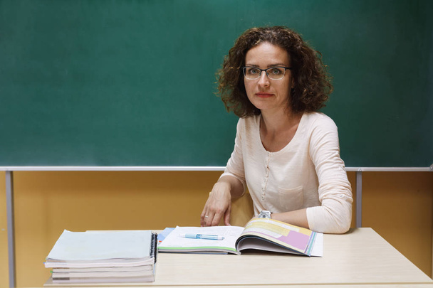 Учитель сидит за школьным столом рядом с доской
 - Фото, изображение
