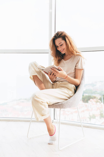 Young pretty woman reading book near window - Zdjęcie, obraz