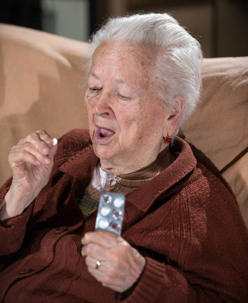 Vanha harmaa tukka sairas nainen ottaa lääkettä
 - Valokuva, kuva