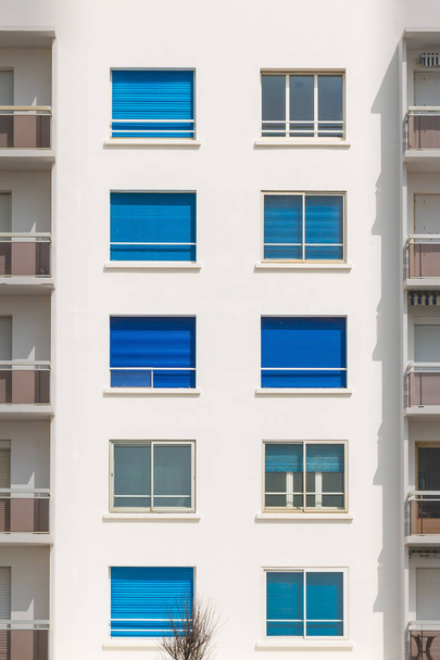 façade du bâtiment avec fenêtres à volets roulants bleus
 - Photo, image