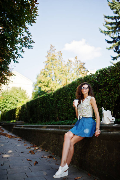 Curly stylish girl wear on blue jeans skirt, blouse and glasses  - Foto, afbeelding
