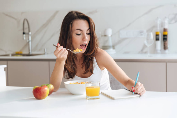 Pretty young woman eating corn flakes cereal for breakfast - Foto, Bild