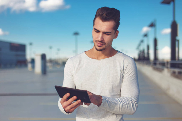 Nuori mies käyttää digitaalista tabletti ulkona, suuri tila
 - Valokuva, kuva