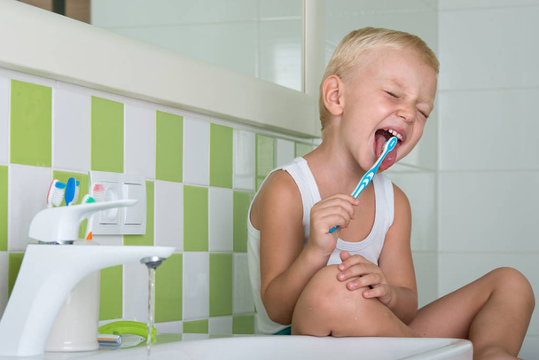 Small boy brushing teeth in the bathroom.The beginning of a new day - Photo, Image