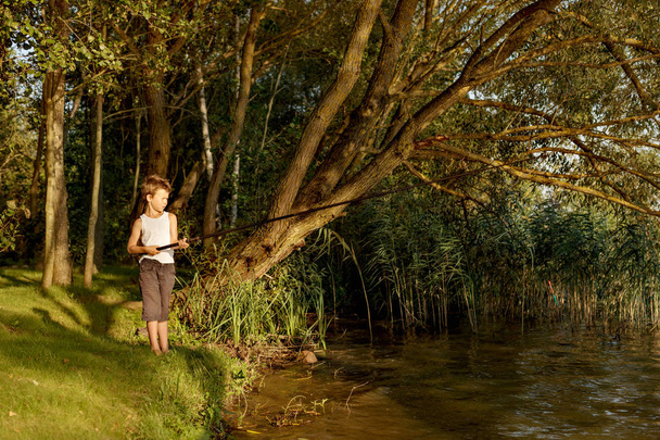 a young boy is fishing in a river - Foto, afbeelding