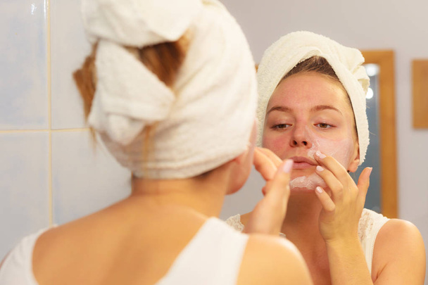 Woman applying mask cream on face in bathroom - Foto, immagini