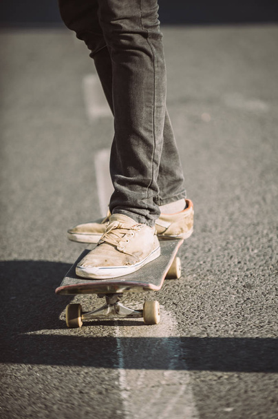 Skateboarder legs riding skateboard on the street - Foto, afbeelding