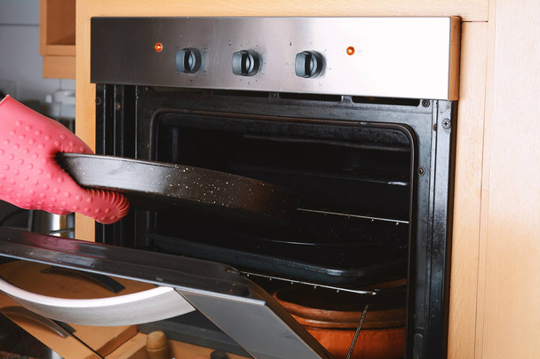 Tomar bandeja horneada del horno con guantes de cocina
 - Foto, Imagen