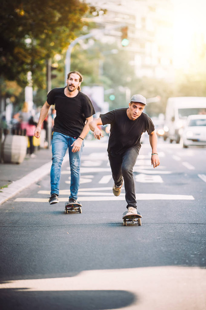 Two skateboarders riding skateboard slope on the city streets - Фото, изображение