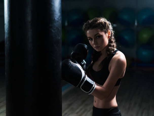 Young fighter boxer girl in training with heavy punching bag - Foto, Bild