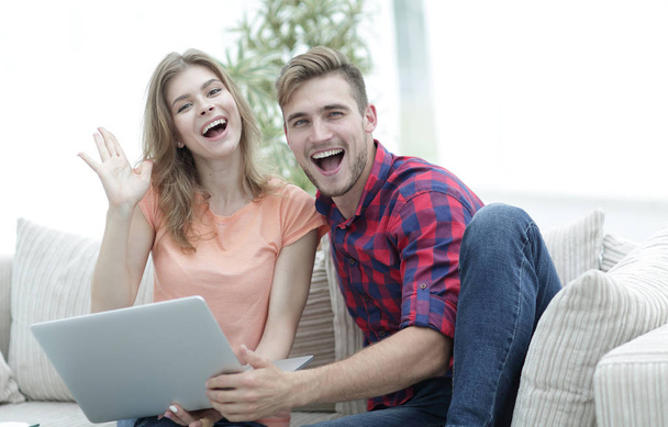 happy couple laughing ,sitting on the couch in front of the open laptop - 写真・画像
