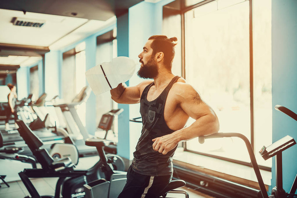 guy relaxing after workout and hold or drink water from big bottle in gym - Foto, Imagem
