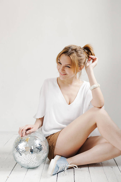 Young hipster woman holding disco ball and posing cheerfully on white background - Фото, зображення