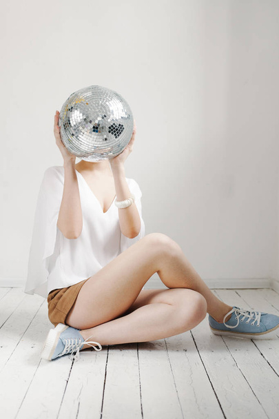 Jovem hipster mulher segurando bola disco e posando alegremente no fundo branco
 - Foto, Imagem