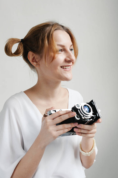 Close up portrait of a smiling pretty girl taking photo on a retro camera isolated over white background - Foto, imagen
