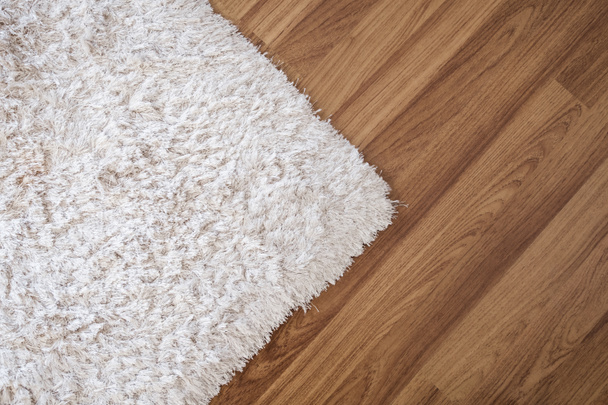 Γκρο πλαν λευκό χαλί στο φυλλόμορφο ξύλινο πάτωμα στο σαλόνι, εσωτερική διακόσμηση - Φωτογραφία, εικόνα