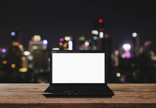 Komputer laptop na biurko z drewna z Bokeh światła miasta na tle nocy. Ekranie komputera ścieżki przycinającej - Zdjęcie, obraz
