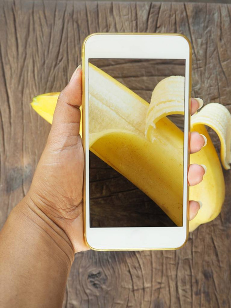 levágott lövés fénykép smartphone banán személy - Fotó, kép