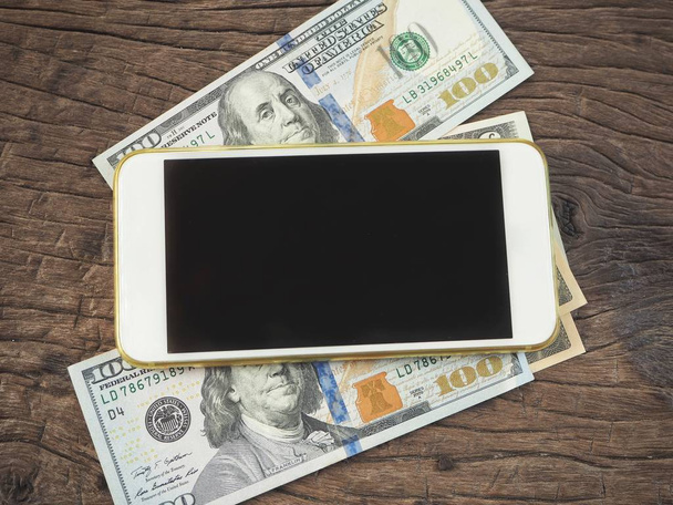 Heap of Dollars lying with smartphone on wooden background - Фото, зображення