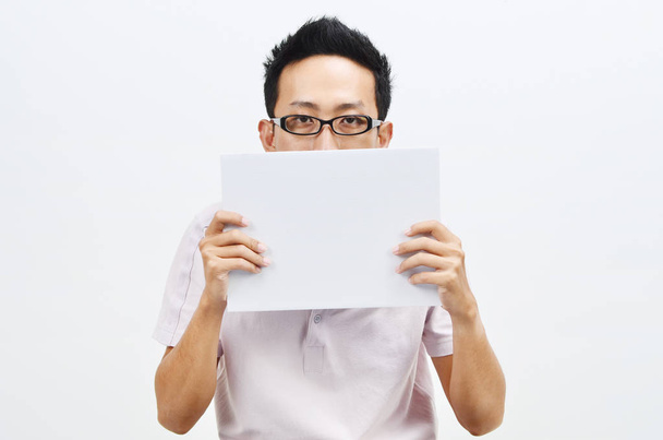 Asian man holding white paper card covering face - Φωτογραφία, εικόνα