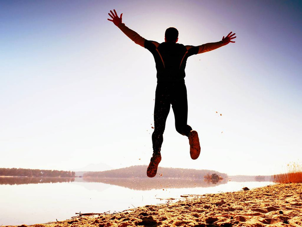 Человек с ума сошел прыгать на пляже. Человек, летящий на пляже во время восхода солнца над головой
 - Фото, изображение